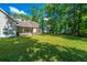 Serene backyard showcasing a covered patio, fire pit, and a sprawling lawn surrounded by trees at 5692 Barbary Coast Rd, Hollywood, SC 29449