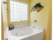 Inviting bathroom featuring a tile-surround tub and a decorative glass block window at 675 Fair Spring Dr, Charleston, SC 29414