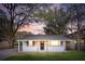 Charming single-story home with white brick, covered porch, and well-lit exterior at dusk at 706 White Oak Dr, Charleston, SC 29407