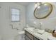 Bathroom with white tile, window, and decorative oval mirror above the vanity and sink at 710 S Magnolia St, Summerville, SC 29483