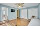 This bedroom features blue walls, wood floors, ceiling fan, and white double door closets at 710 S Magnolia St, Summerville, SC 29483