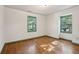 A bedroom with hardwood floors, two windows with green trim, and white walls at 810 Creekside Dr, Mount Pleasant, SC 29464