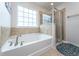 Bright bathroom featuring a soaking tub with tile surround and glass-enclosed shower at 9767 Black Willow Ln, Ladson, SC 29456