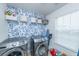 Well-organized laundry room with a washer and dryer, shelving and a floral accent wall at 9767 Black Willow Ln, Ladson, SC 29456
