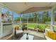 Relaxing screened-in porch with wicker furniture, a stylish glass coffee table, and views of the landscaped yard at 9767 Black Willow Ln, Ladson, SC 29456