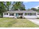 Charming one-story home with white brick exterior, well-manicured lawn, and a bright blue front door at 105 Evatt Dr, Goose Creek, SC 29445