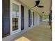 A long outdoor porch with wooden floors, black ceiling fans, and dark window shutters, for relaxing and enjoying the outdoor at 108 Mourning Dove Dr, Bonneau, SC 29431