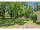 Large backyard with lush green grass, mature trees, storage shed, and docked boat at 1192 Church Of God Rd, Bonneau, SC 29431