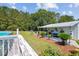 Landscaped backyard with a covered patio, above-ground pool, and lush greenery, perfect for outdoor relaxation at 131 Travis Hill Rd, Moncks Corner, SC 29461