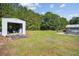 Expansive backyard featuring a well-maintained lawn, detached garage with open door, and greenery at 131 Travis Hill Rd, Moncks Corner, SC 29461