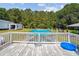 Elevated view of an above-ground pool with white railing and weathered wooden deck, surrounded by trees and greenery at 131 Travis Hill Rd, Moncks Corner, SC 29461