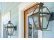 Close up of a stylish dark bronze exterior lantern near a glass paneled stained wooden front door at 1502 Menhaden Ln, Mount Pleasant, SC 29466
