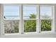 Three windows with white frames showing the natural view of trees and water at 1502 Menhaden Ln, Mount Pleasant, SC 29466
