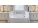 Bright bathroom featuring a white soaking tub surrounded by matching white cabinets and mirrors at 1511 Hopkins Ln, Mount Pleasant, SC 29466