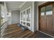 Inviting porch featuring a wood floor, gray siding, and dark wood front door at 1518 Bower Ln, Johns Island, SC 29455