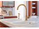Close-up of kitchen sink with brass fixtures, marble countertops, and stainless steel appliances at 155 Wentworth St # A, Charleston, SC 29401