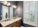 Bathroom with dual sinks, granite countertops, dark blue walls, and a window with white shutters at 1629 Ware Bottom Ln, Mount Pleasant, SC 29464