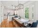Bright dining area with a rustic wooden table, modern lighting, and a view of the lush outdoors through shuttered windows at 1629 Ware Bottom Ln, Mount Pleasant, SC 29464