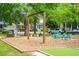 Community playground featuring swings, playhouse, seating, and mulched area, surrounded by trees at 1629 Ware Bottom Ln, Mount Pleasant, SC 29464