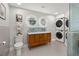 Bright bathroom featuring double sink vanity, lighted mirrors, hexagonal floor tiles, and stacked washer dryer unit at 1673 Mcclain St, Charleston, SC 29407