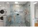 Modern shower with beautiful tile work, built-in shelves, and a glass enclosure, plus stacked washer/dryer at 1673 Mcclain St, Charleston, SC 29407