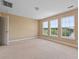 Spacious bedroom with three windows showcasing green trees and water views, plus a door for easy access at 1825 Brittlebush Ln, Johns Island, SC 29455