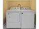 Well-lit laundry room features a white washer and dryer set with overhead shelving at 1825 Brittlebush Ln, Johns Island, SC 29455
