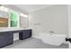 Bright bathroom featuring a soaking tub and dual sink vanity with black cabinets and elegant fixtures at 202 Countryside Way, Summerville, SC 29483