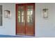 An elegant wood front door with glass panels and decorative sconces at 2151 River Road, Johns Island, SC 29455