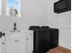 Modern laundry room features black washer and dryer, white cabinets, and stylish fixtures at 2151 River Road, Johns Island, SC 29455