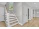 Bright hallway featuring hardwood floors, neutral paint, staircase to the second level, and several access doors at 2197 Sandy Point Ln, Mount Pleasant, SC 29466