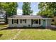 Charming one-story home with a teal door and black shutters, surrounded by lush trees at 2219 Eagle Dr, North Charleston, SC 29406