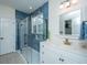 Modern bathroom with walk-in shower, blue tile, and white vanity with stone countertop and golden faucet at 2324 High Tide Dr, Charleston, SC 29414