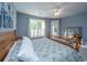 Comfortable bedroom with blue walls, wooden bed, ceiling fan, and large window offering ample natural light at 2324 High Tide Dr, Charleston, SC 29414