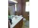 A modest bathroom featuring a mirror, single sink, toilet, and shower with wood paneled walls at 2604 Palmetto Blvd, Edisto Island, SC 29438
