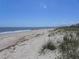Expansive beach view with sandy dunes, calming ocean waves, and blue skies at 2604 Palmetto Blvd, Edisto Island, SC 29438