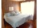 Cozy bedroom featuring hardwood floors, wood-paneled walls, and a comfortable bed with bright light at 2604 Palmetto Blvd, Edisto Island, SC 29438