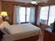 Comfortable bedroom with white linens, wood-paneled walls, and natural light from multiple windows at 2604 Palmetto Blvd, Edisto Island, SC 29438