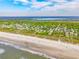 Scenic aerial view of coastal homes nestled among lush greenery, bordering a sandy beach and ocean at 3301 Palm Blvd, Isle of Palms, SC 29451