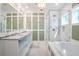 Bright bathroom featuring a double vanity, marble countertops, and glass-enclosed shower with separate tub at 3301 Palm Blvd, Isle of Palms, SC 29451