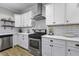 Close up shot of a white kitchen with stainless steel appliances, white subway tile backsplash, and floating shelves at 3361 Olivia Marie Ln, Johns Island, SC 29455