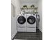 Efficient laundry room with front loading washer and dryer, modern shelving, and stylish black tiled flooring at 3361 Olivia Marie Ln, Johns Island, SC 29455