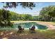 Scenic pond view with two Adirondack chairs, lush trees, and a tranquil atmosphere under a bright blue sky at 3361 Olivia Marie Ln, Johns Island, SC 29455