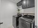 Modern laundry room featuring black front load washer and dryer with dark cabinets and wood shelf at 401 Carrara Dr, Summerville, SC 29486