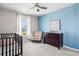 Bedroom room with paneled accent wall, crib, rocking chair, dresser, ceiling fan and natural light from window at 4024 Exploration Rd, Ladson, SC 29456