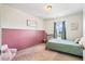 Cozy bedroom with a large patterned rug, a pastel pink accent wall, and natural light from the window at 4024 Exploration Rd, Ladson, SC 29456