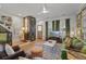 Charming living room with stylish wallpaper, shuttered windows, green velvet sofa and open layout to a cozy dining area at 404 Forsythia Ave, Summerville, SC 29483