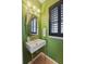 Stylish powder room features green walls, statement mirror, modern lighting, and black shutters, adding a touch of elegance at 404 Forsythia Ave, Summerville, SC 29483