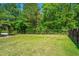 Spacious backyard with a wooden fence, mature trees, and lush green grass, offering privacy at 409 Carousel Ct, Summerville, SC 29483