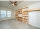 A spacious bedroom with carpet, a ceiling fan, two windows, and a custom-built shelving unit at 409 Carousel Ct, Summerville, SC 29483